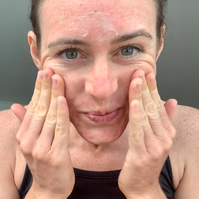 Katie Jackson rubbing RoC Retinol Serum on her face.