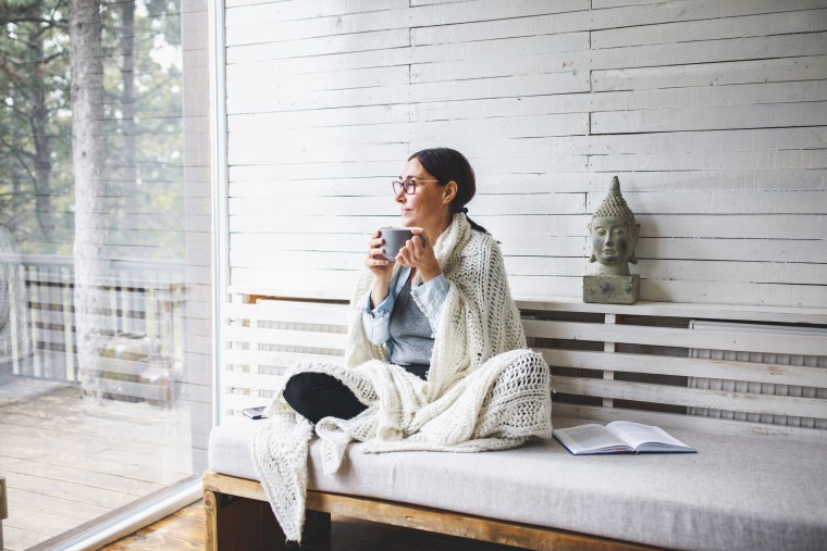 Woman sitting comfortable and looking through the window. See the best teas for your health. Learn about the health benefits of teas and shop matcha green tea, oolong tea and more to add to your daily routine.