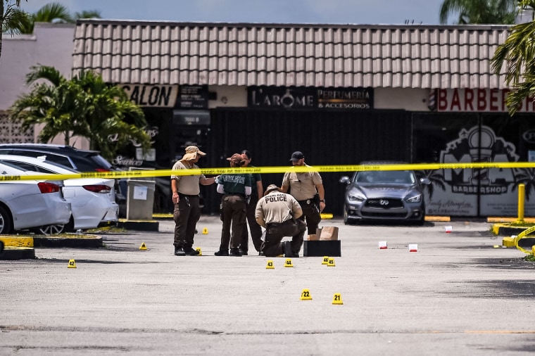 Police collect evidence from the parking lot in front of a club where three gunmen killed two people and injured 20 overnight in Hialeah, Fla., on May 30, 2021.