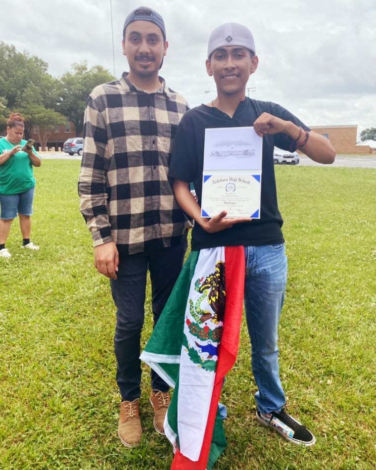 Asheboro High School senior Ever Lopez holds up his diploma as he poses with his cousin, Adolfo Hurtado.