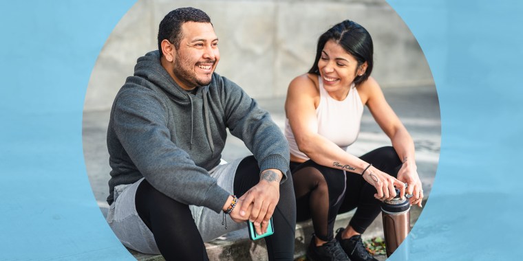 Man and Woman sitting on the pavement wearing workout gear