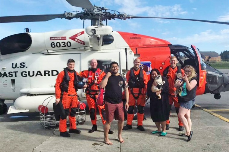 The rescued adults pose with their two dogs and members of the U.S. Coast Guard.