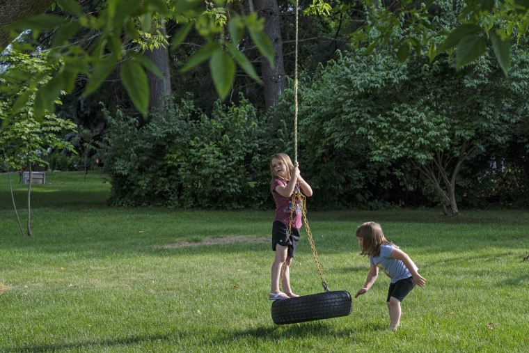 Maggie and McKenzie Whitlock play on their tire swing at home.