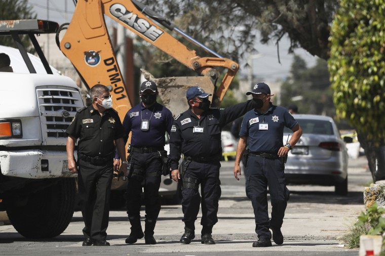 Police walk outside the house where bones were found under the floor in the Atizapan municipality in Mexico, on May 20, 2021.