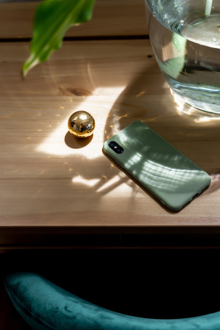 Mobile phone by golden ball on wooden desk in bedroom at home