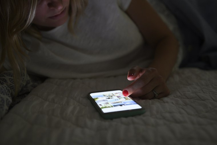 Woman scrolling through social media on smart phone at night