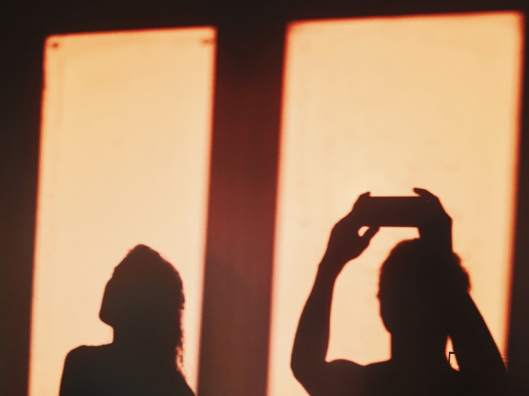 Shadow Of Woman By Man Photographing On Wall