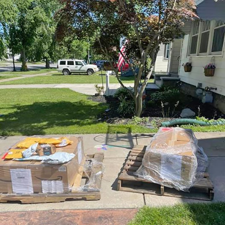 piles of boxes sit on the driveway of a suburban neighborhood