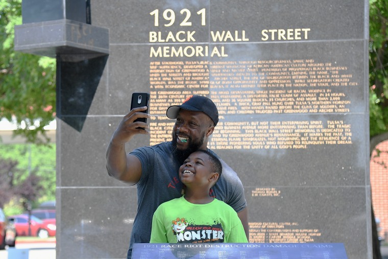 A father and son take a selfie at the Black Wall Street Memorial