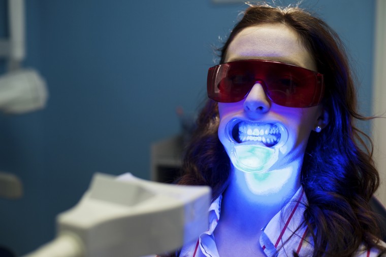 A woman wears protective eyewear during a teeth whitening session.