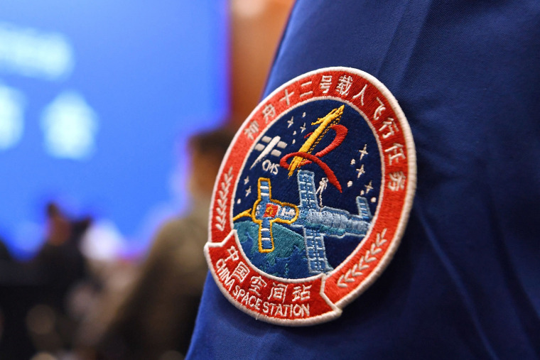 Image: A staff member of the Jiuquan Satellite Launch Centre wears the logo of China's new space station during a press conference about the first crewed mission to the station, China