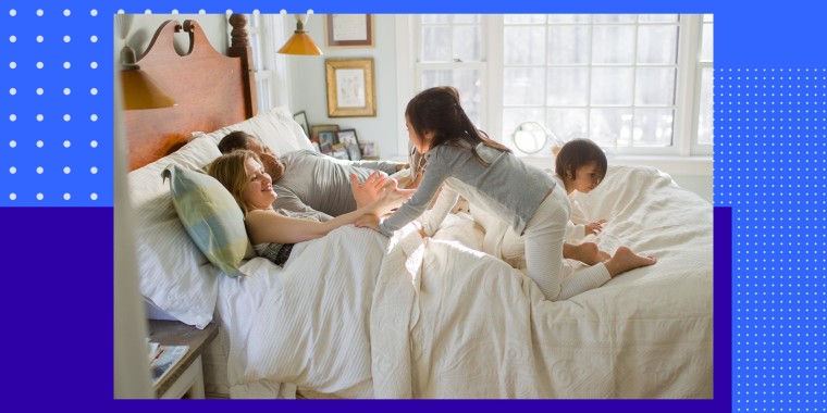 Parents with two kids playing in bedroom on bed
