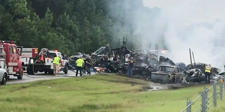 Image: Emergency personnel work at the accident site as smoke rises from the wreckage after about 18 vehicles slammed together on a rain-drenched Alabama highway during Tropical Storm Claudette, in Butler County, Alabama