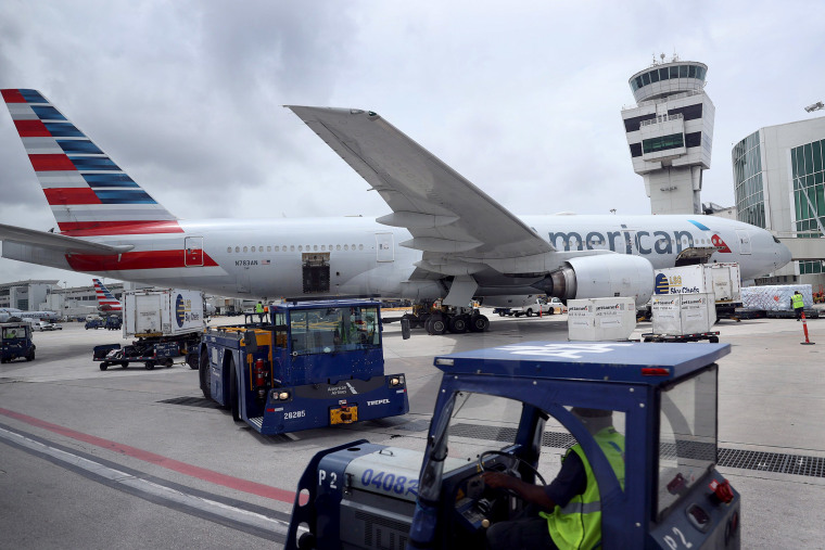 Image: Workers prepare an American Airlines plane at a gate before its flight from the Miami International Airport