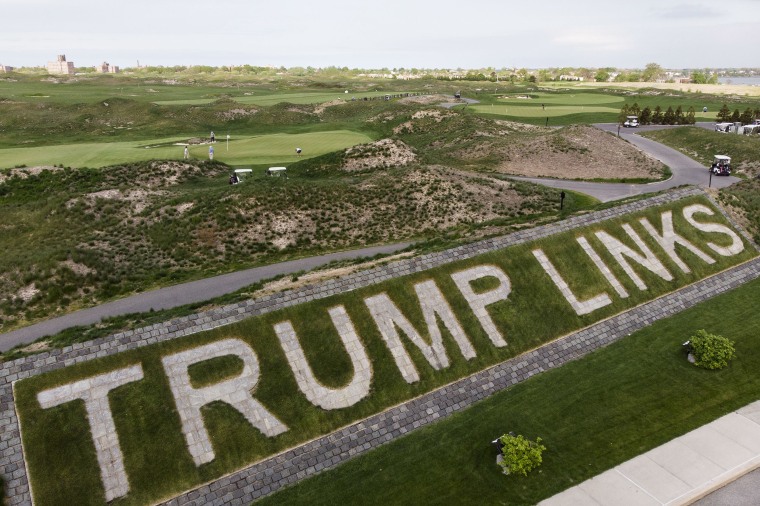 Image: Patrons play the links as a giant branding sign is displayed with flagstones at Trump Golf Links at Ferry Point in the Bronx borough of New York