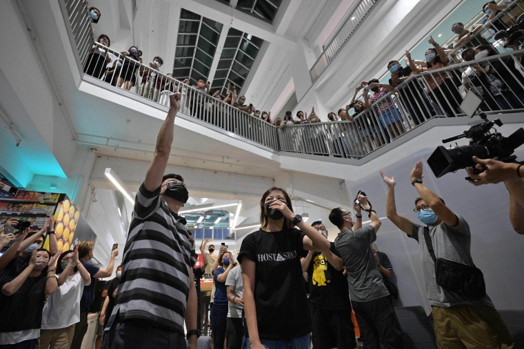Image: Employees, executive editor in chief Lam Man-Chung, left, and deputy chief editor Chan Pui-Man, center, cheer each other in the Apple Daily newspaper office atrium after the newspaper went to print for the last time, Hong Kong