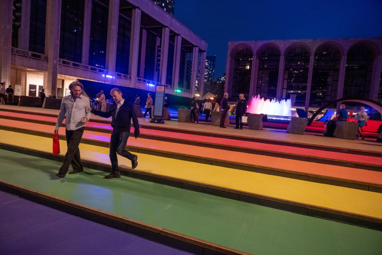 People walk on the stairs covered in Pride colors at Lincoln Center for the Performing Arts on June 2, 2021, in New York.