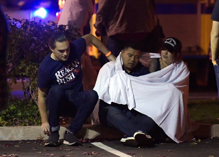 People comfort one another after a gunman killed twelve people at the Borderline Bar and Grill