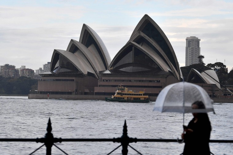 Image: A woman walks in front of the Opera House in Sydney, as the usually busy streets of Sydney, Brisbane, Perth and Darwin have fallen quiet with millions of Australians under stay-at-home orders to control the highly contagious Delta variant