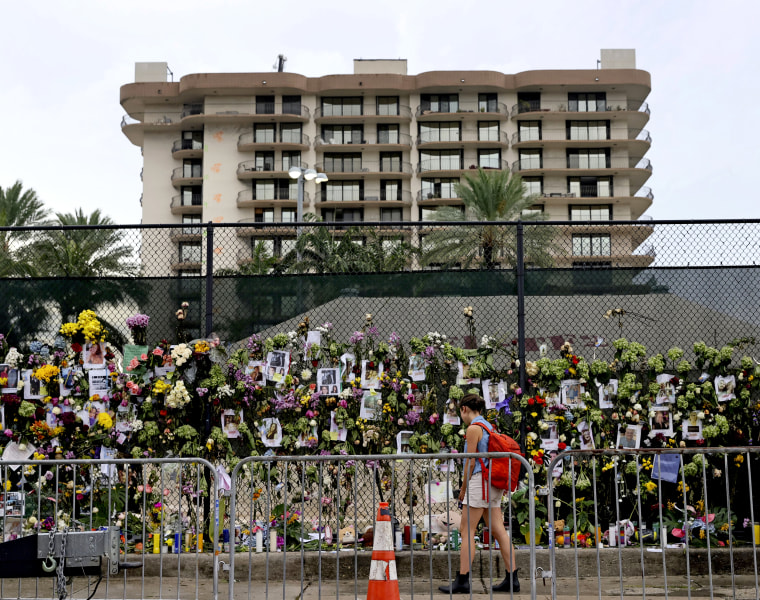 Image: A woman visits the memorial wall full of photos of the missing and messages of love, support and prayers at Harding Avenue and 86th Street as search and rescue personnel continue to look for survivors in the rubble of the Champlain Towers