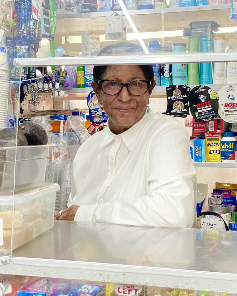 Nidia Bello, stands behind the counter of her bodega in Washington Heights, N.Y.