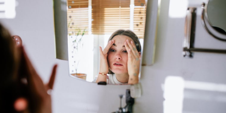Woman looking in bathroom mirror after cleaning her face