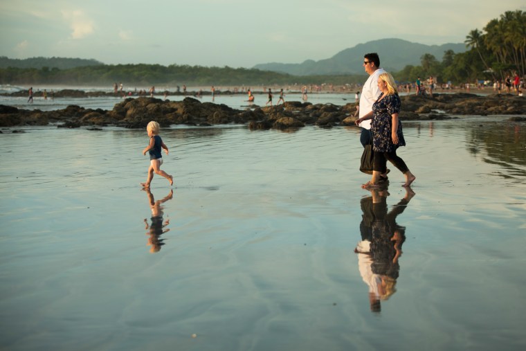 Jeromy Sonne, Kelsey Sonne, and their son Emmett walk on the beach in Tamarindo, Guanacaste, Costa Rica.