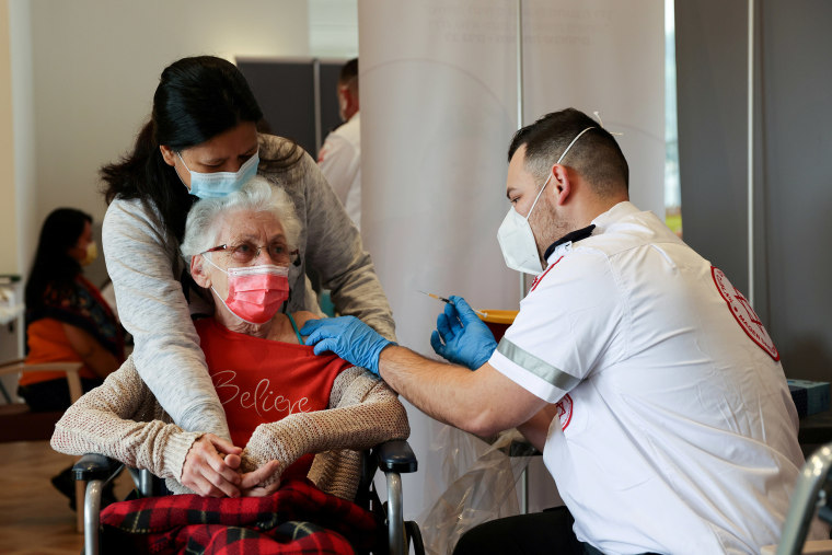 Image: An elderly woman receives a booster shot of her vaccination at an assisted living facility, in Netanya