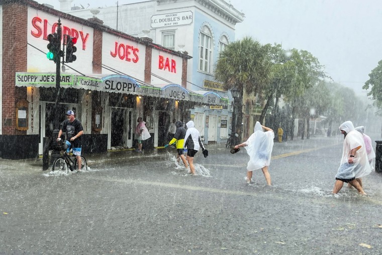 Determined visitors head for Sloppy Joe's Bar while crossing a flooded Duval Street as heavy winds and rain pass over Key West, Fla., on July 6, 2021.