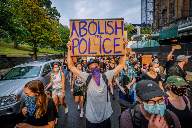 Image A participant holding a Abolish Police sign at a protest.