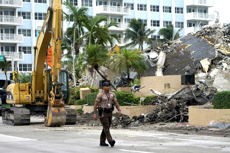 Image: A police officer walks past the collapsed and demolished Champlain Towers South condominium building.