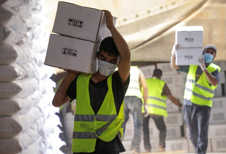 Image: Workers carry boxes of humanitarian aid near Bab al-Hawa crossing at the Syrian-Turkish border.