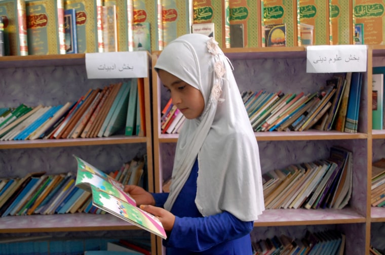 Image: A pupil reads a book in the library at the Um-Salma.
