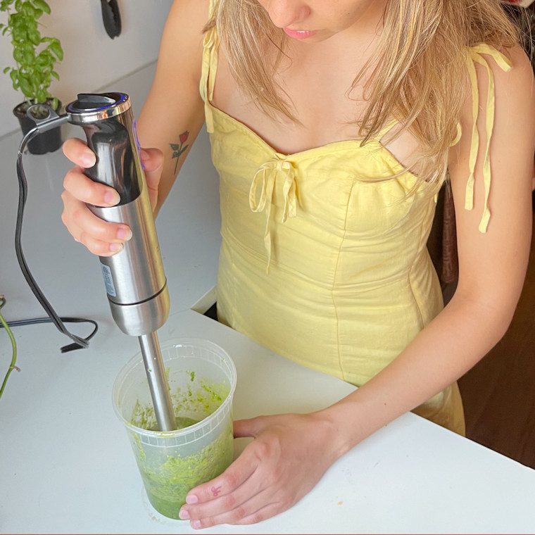 Cailey Rizzo using an immersion blender in her kitchen.