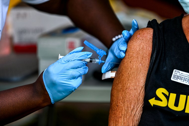 healthcare worker administers a Johnson and Johnson Covid-19 vaccine to a homeless woman at a vaccination mobile unit setup by Miami Dade County Homeless Trust in Miami, on May 13, 2021.