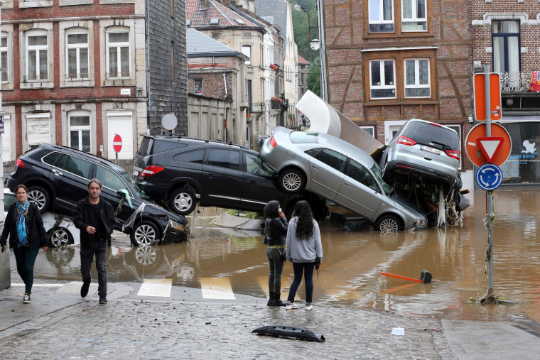 People passing by cars piled up at a roundabout in the Belgian city of Verviers on July 15, 2021.