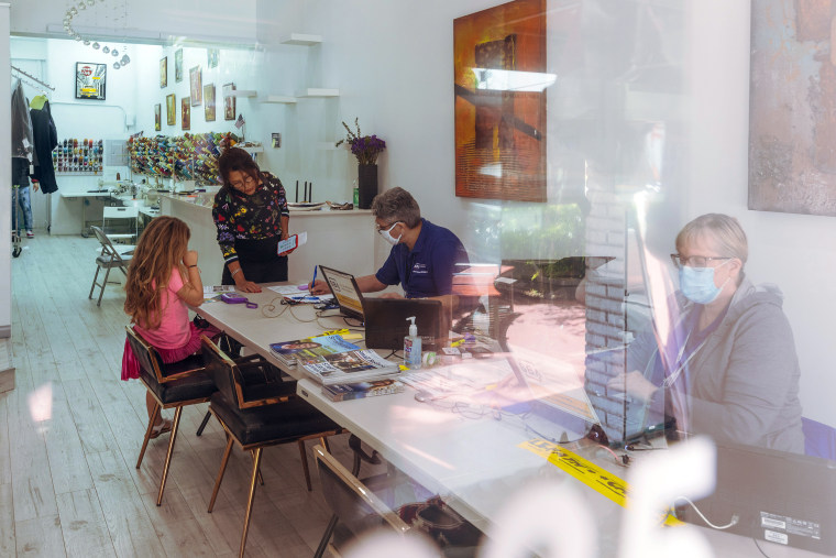 Image: Asuncion Guerrero, center, and Paula Ferguson, right, of The Small Business Association (SBA) assist people with disaster recovery on July 14, 2021 in Surfside, Fla.