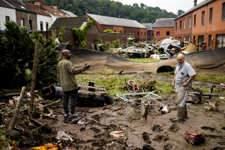 Image: Two residents speak with each other as they clean up after flooding in Ensival, Verviers, Belgium, on July 16, 2021.