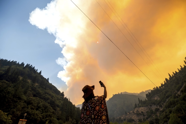 Jessica Bell takes a video as the Dixie Fire burns along Highway 70 in Plumas National Forest, Calif., on Friday.