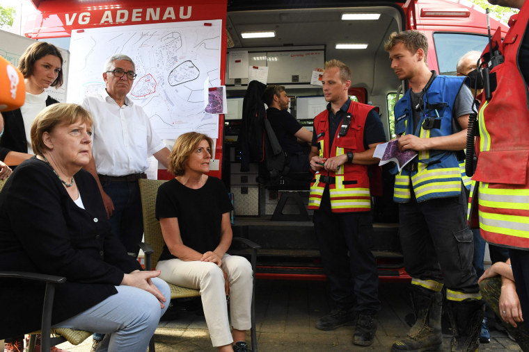 German Chancellor Angela Merkel and Rhineland-Palatinate State Premier Malu Dreyer talk to helpers during their visit to the flood-ravaged village of Schuld on July 18, 2021.