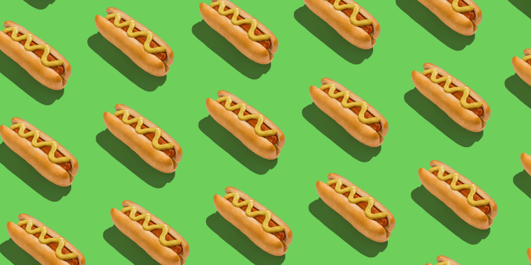 Lots of classic hotdogs with mustard sause over green background, creative pattern