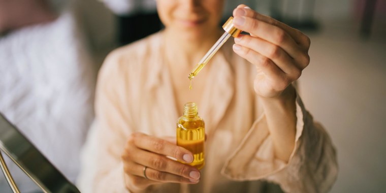 Image of Woman holding natural face oil in her bedroom