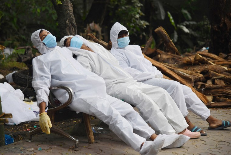 Image: Ambulance staff rest on a bench after their Covid-19 coronavirus duty at a crematorium ground in Guwahati, India