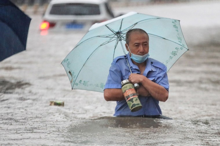 Image: A man wading through flood waters along a street following heavy rains in Zhengzhou in China's central Henan province,