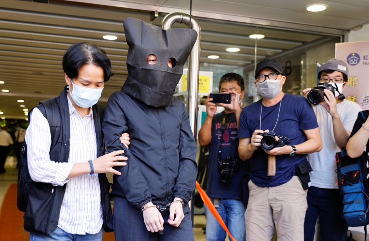 Image: Police escort one of five suspects, detained on suspicion of publishing and distributing seditious material, in Hong Kong