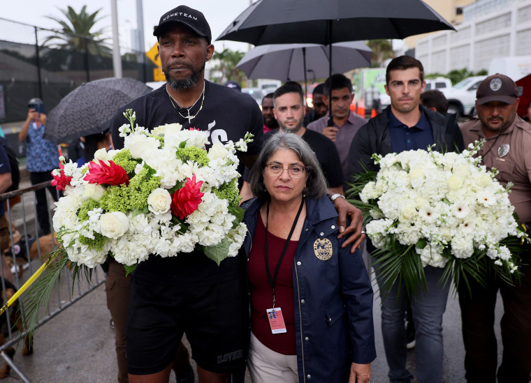 Image: Udonis Haslem of the Miami Heat and Miami-Dade County Mayor Daniella Levine Cava arrive at a memorial after the Champlain Towers South building collapse on June 30, 2021 in Surfside, Fla.