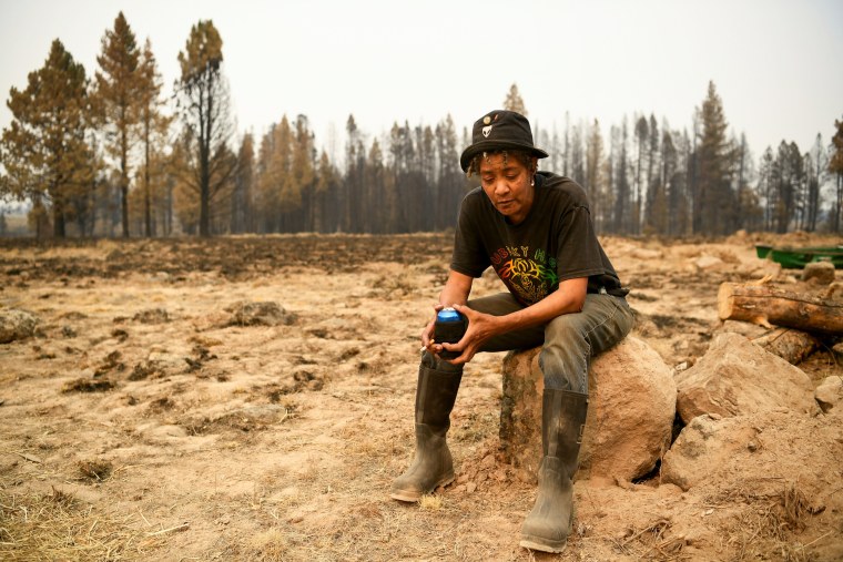 Pam Brown sits on a small boulder while grieving her losses from the Bootleg Fire in Sycan Estates, Ore., on July 24, 2021.