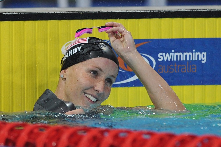 a swimmer in a pool takes her pink goggles off 