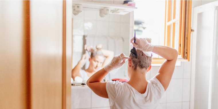 Woman dyeing hair in front of mirror