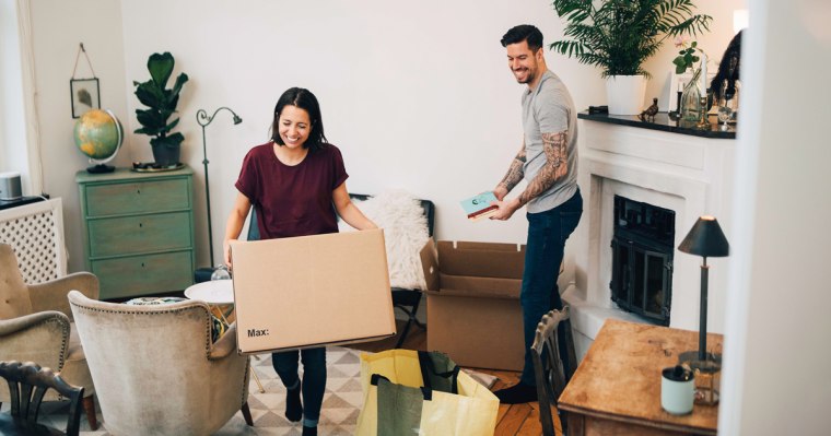 Happy couple unpacking boxes in living room at new home